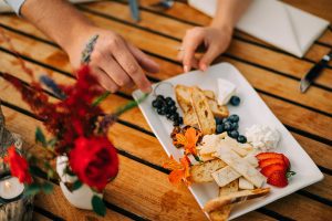 Hands of couple selecting items from cheese plate.